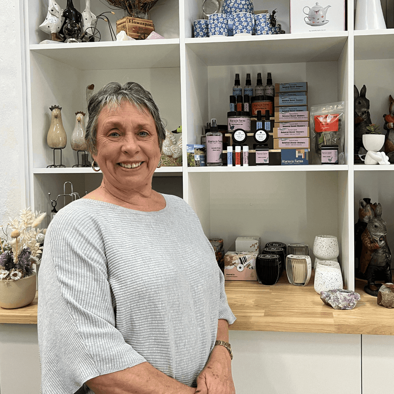 Ataraxis Farms stockist Oopsa Daizies Wendy standing in front of Ataraxis Farms products on a shelf